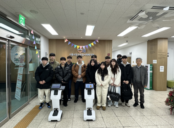 한국공학대학교 지능형로봇 혁신융합대학사업단이 시흥시 장곡종합사회복지관에서 모바일로봇을 활용한 지역사회 문제 해결 발표회를 개최했다. 발표회 참석자들이 모바일로봇 ‘Temi’와 함께 기념사진을 촬영하고 있다